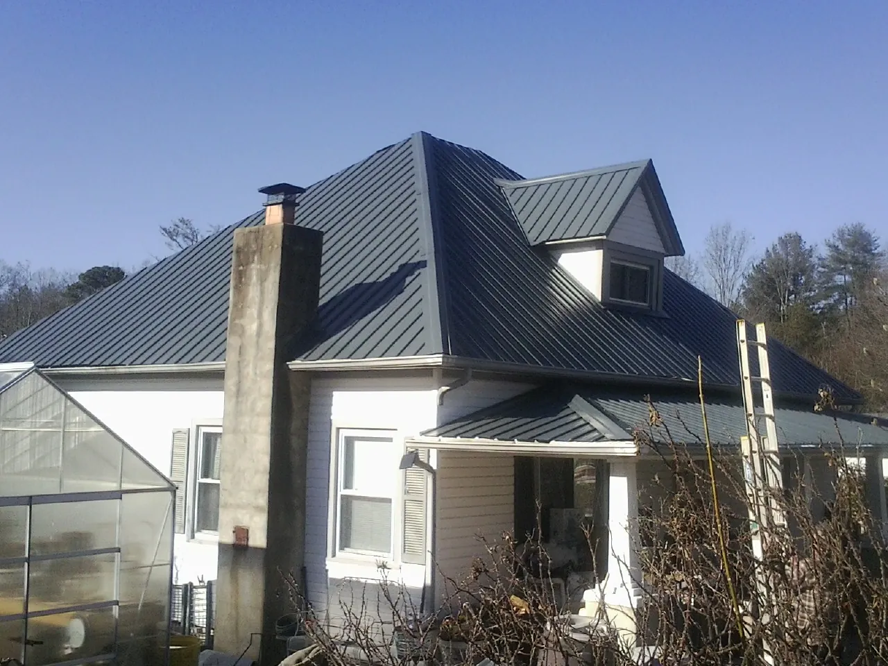 Dark blue standing seam metal roof on a white farmhouse with dormer — Slate & Tile Roof Repair by Roofing Brothers in Salmon