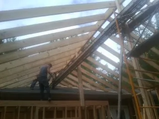 Rafters going up over a new addition with a worker on the wall in Salmon