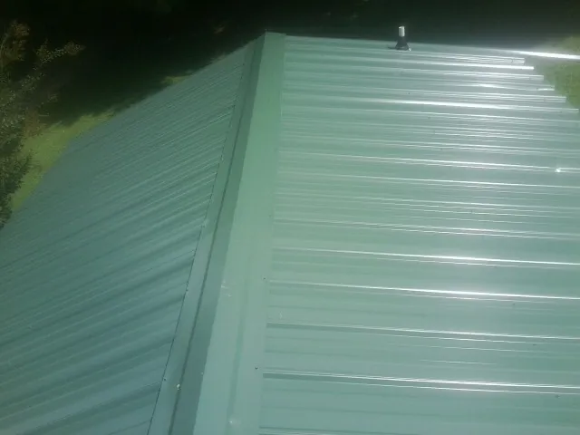 New green metal panels meeting at the ridge of a roof — Flat Roof Repair work by our crew in Salmon