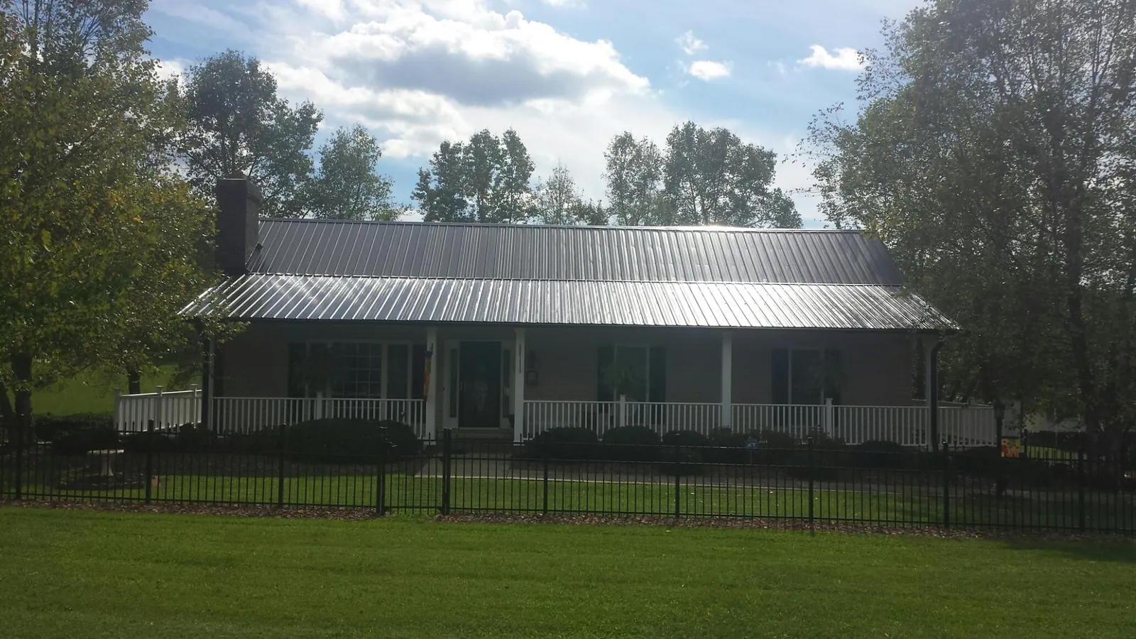 Gray metal roof on a brick ranch with a full width front porch — Gutter Guard Installation work by our crew in Salmon