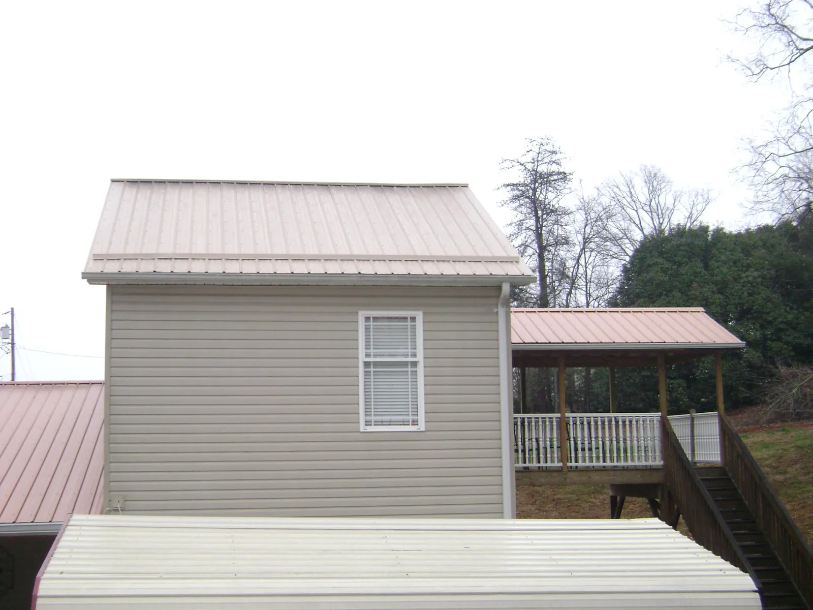 Tan metal roofs on a two story addition and attached porch, from a Roof Replacement job in Salmon