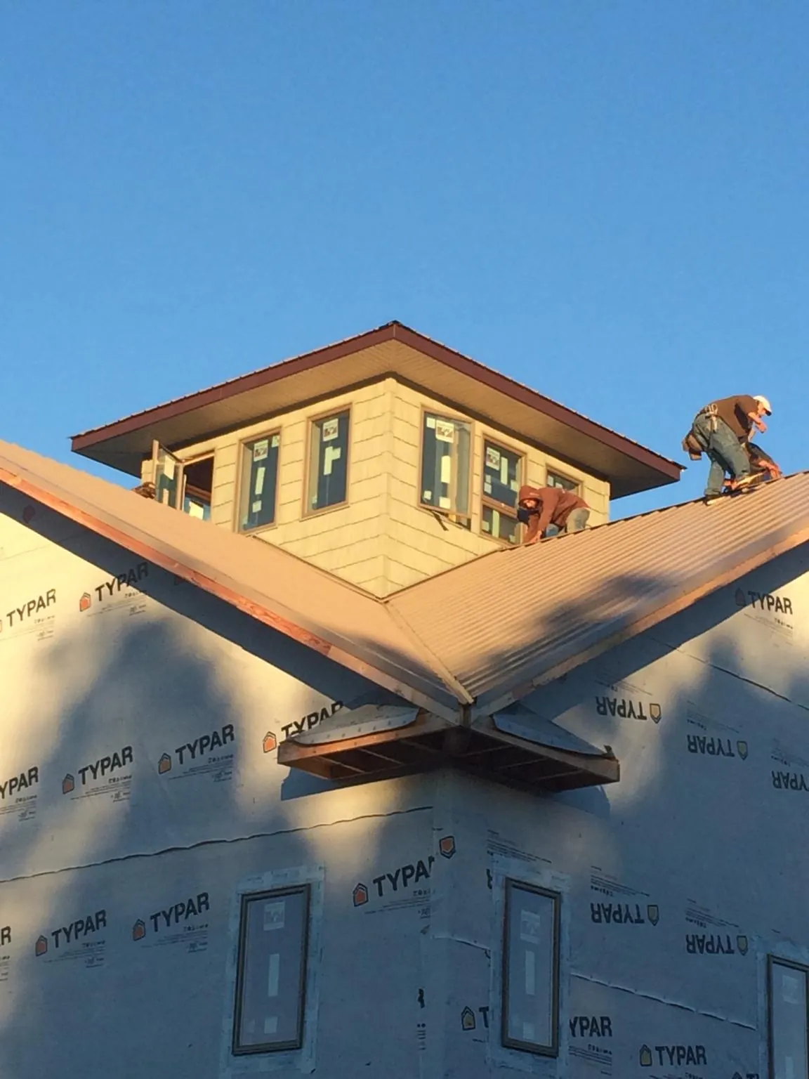Roofers working around a rooftop cupola on a new metal roof at sunset — Roof Waterproofing in Salmon by Roofing Brothers